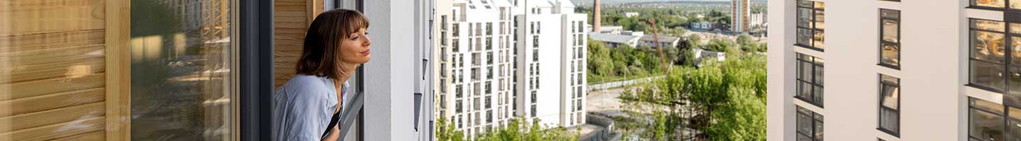 Femme penché à la fenêtre de son appartement